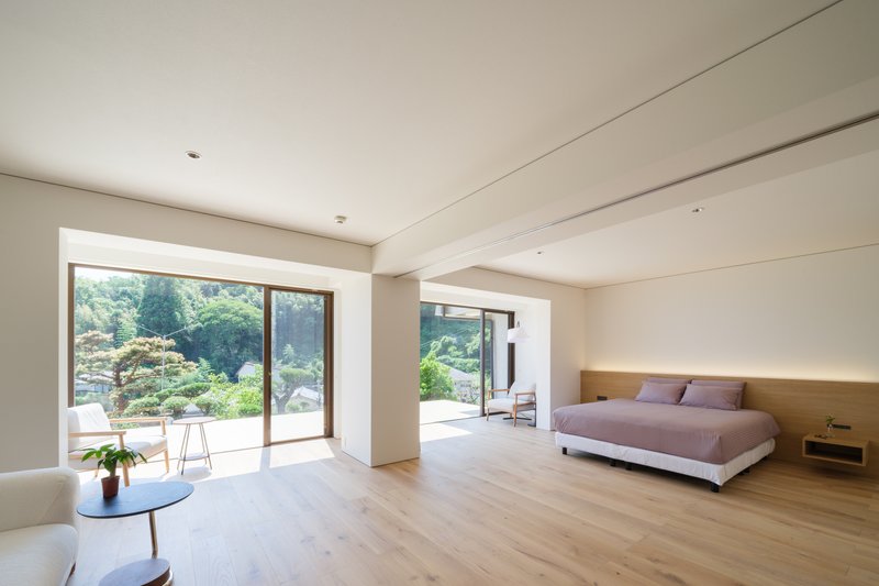 Bedroom with timber headboard wall and glass doors framing views of a sculptural garden and terrace