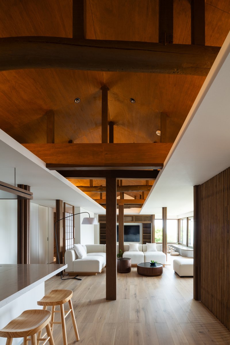 View through the double-height space with freestanding timber columns and layered ceiling planes overhead