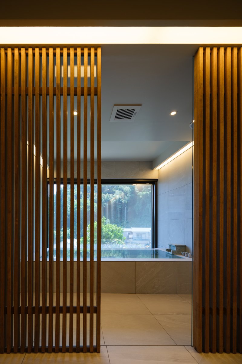 Backlit vertical timber slat screens flanking entrance to bathroom with garden view window
