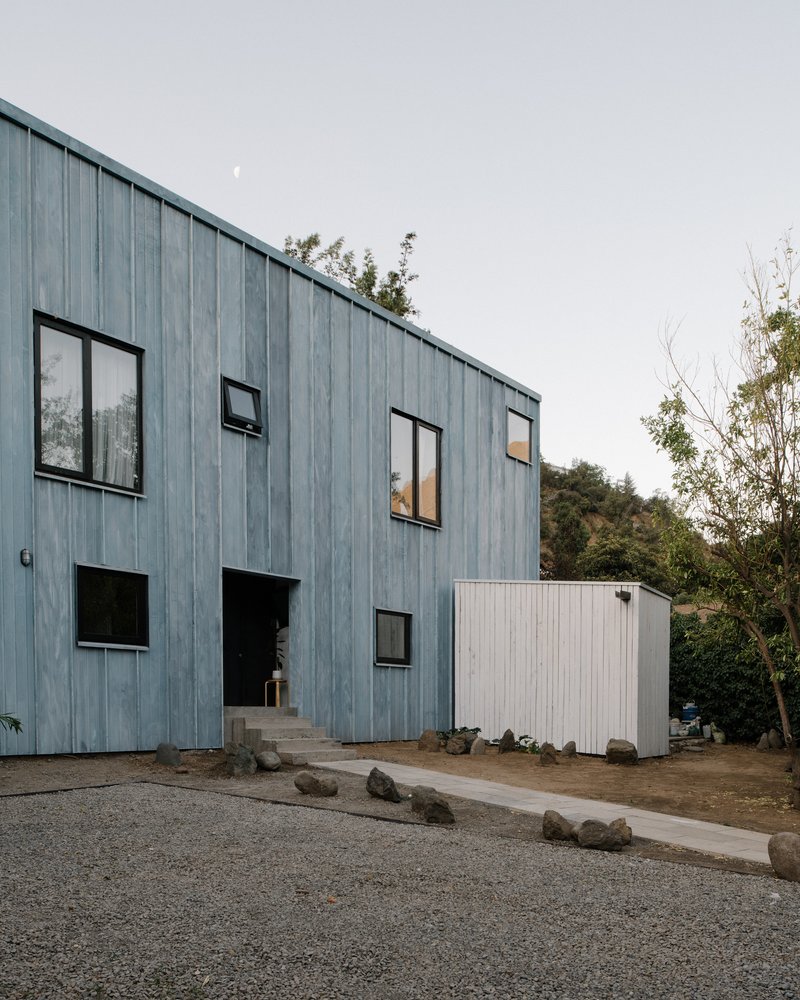 Vertical timber cladding facade with scattered windows and concrete entry steps under overcast sky