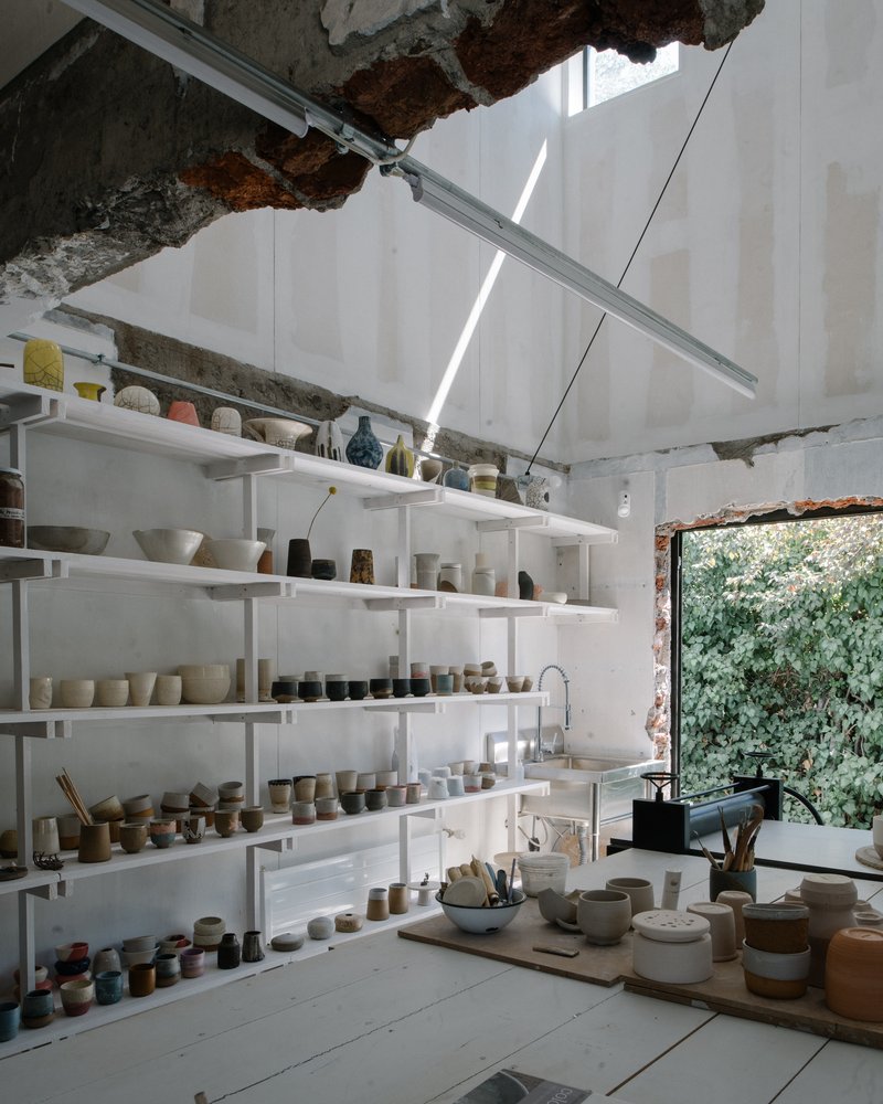 Pottery workshop with white shelving and exposed brick openings under skylit ceiling