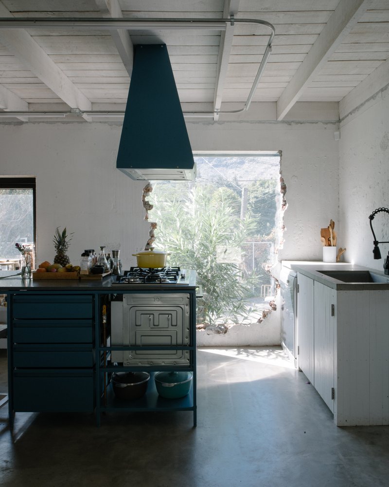Kitchen with dark blue hood and range framed by a wide window opening