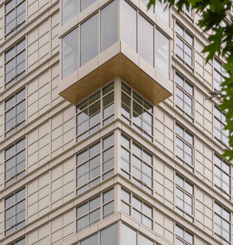 Corner balcony detail with timber soffit projecting from gridded white panel facade