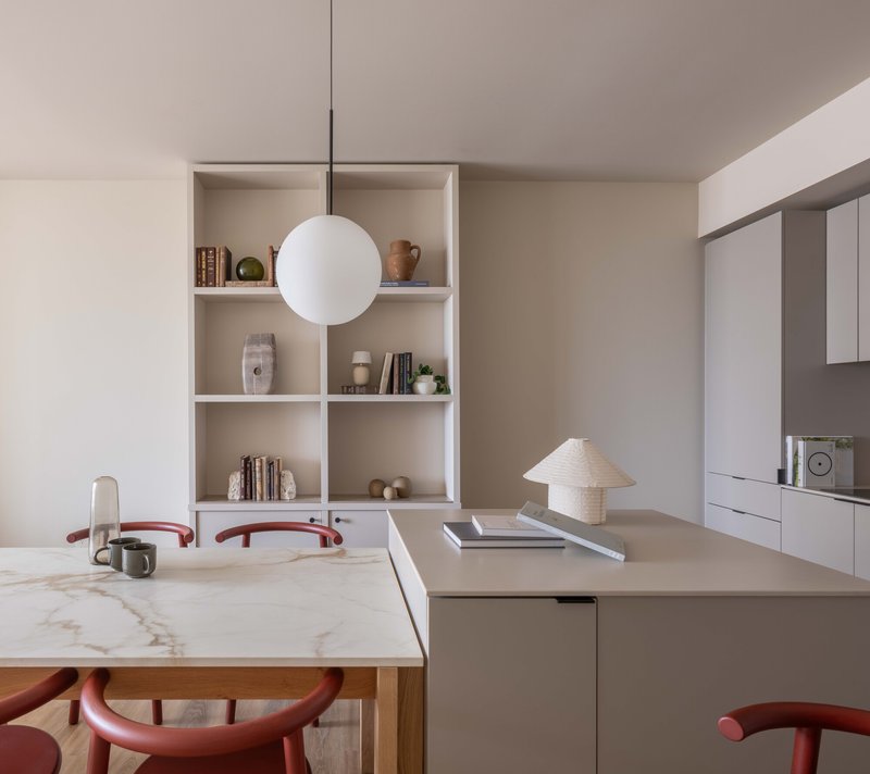 Open kitchen and dining area with marble table, built-in shelving, and spherical pendant light
