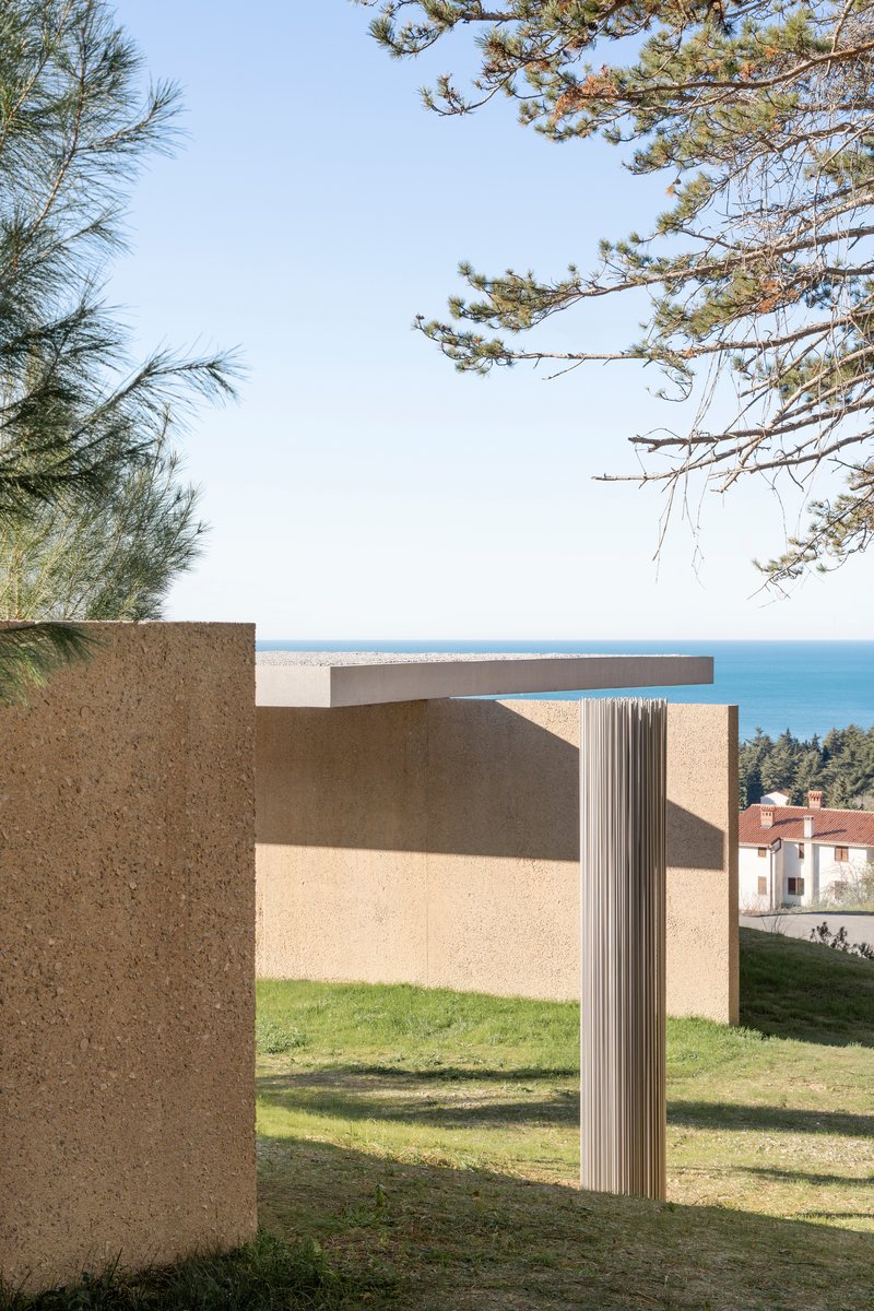 Fluted column detail between stucco walls with ocean views and pine branches overhead