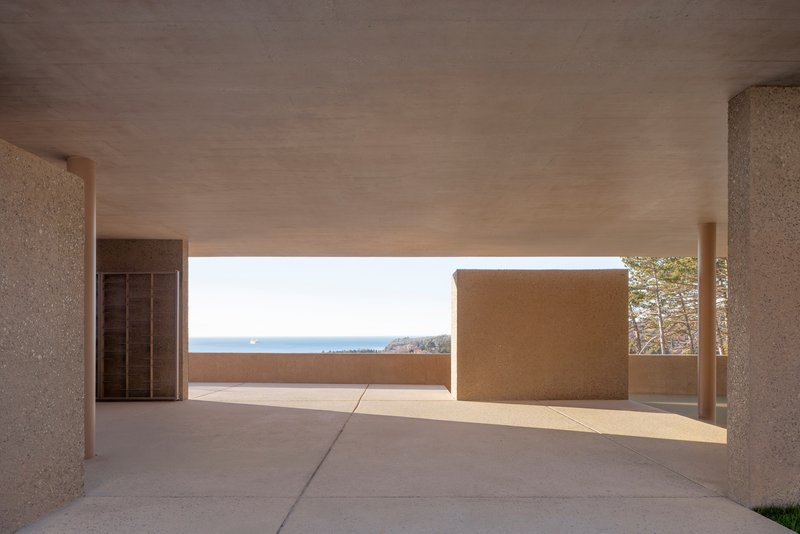 Open-air terrace framed by columns with sea horizon visible beyond low parapet wall