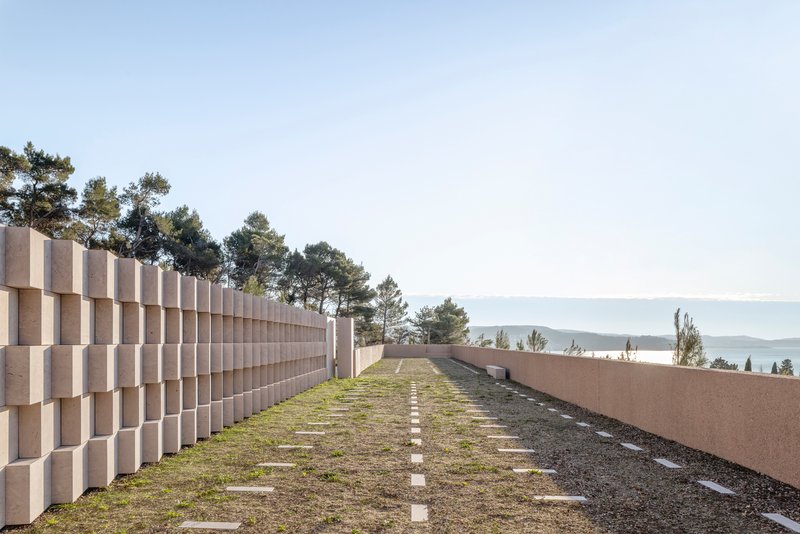 Green roof pathway between a stacked block wall and a cor-ten steel parapet overlooking distant water