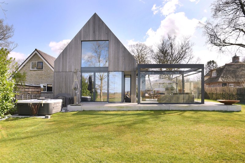 Rear garden view showing the gabled timber volume and glazed extension framed by bare winter trees