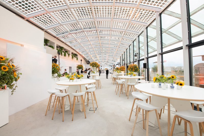 Interior dining space with latticed curved ceiling and floor-to-ceiling glazing along one side