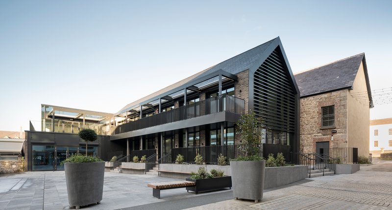 Two-story glazed facade with black metal railings and slate-roofed gable end against clear sky