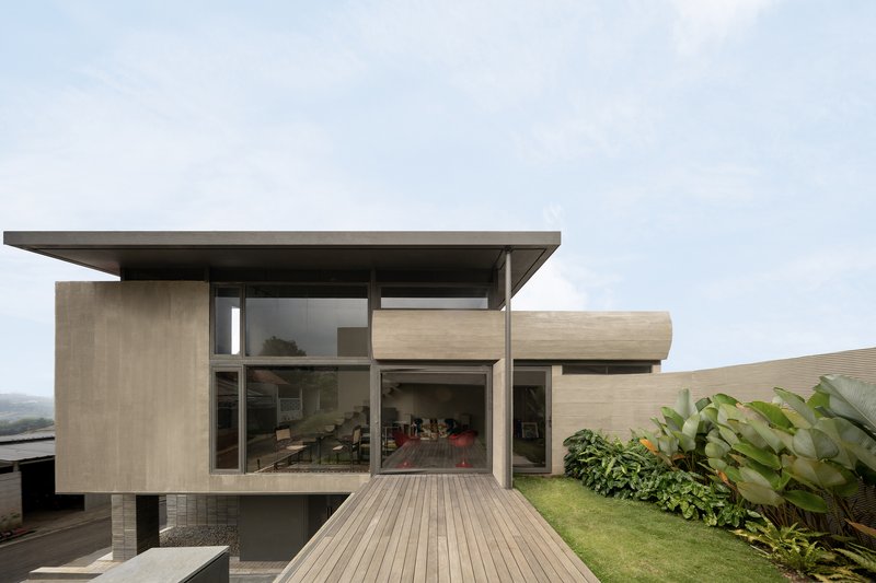 Garden facade with timber deck leading to the glass-walled living room beneath a flat roof overhang