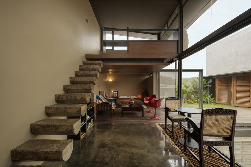 Interior living space with floating concrete staircase and double-height glazing overlooking the deck
