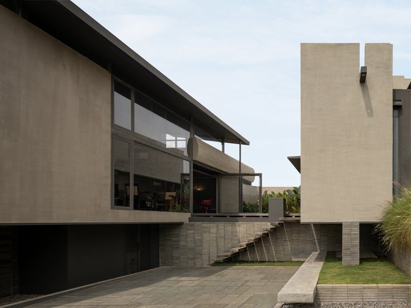 Rear elevation showing glazed volumes elevated on striped masonry plinths with sloping lawn below