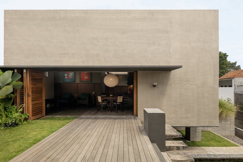 Timber deck leading to an open living area framed by vertical wood slats and tropical plants
