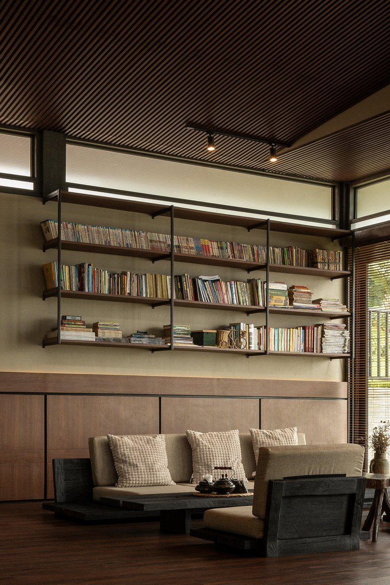 Built-in bookshelf beneath clerestory windows with timber slat ceiling and afternoon sunlight