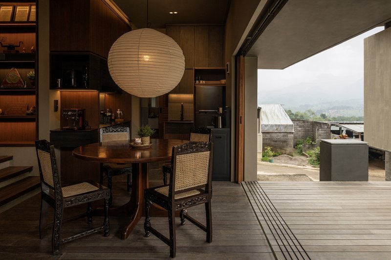 Dining area with paper lantern opening onto timber deck terrace overlooking distant village rooftops in mist