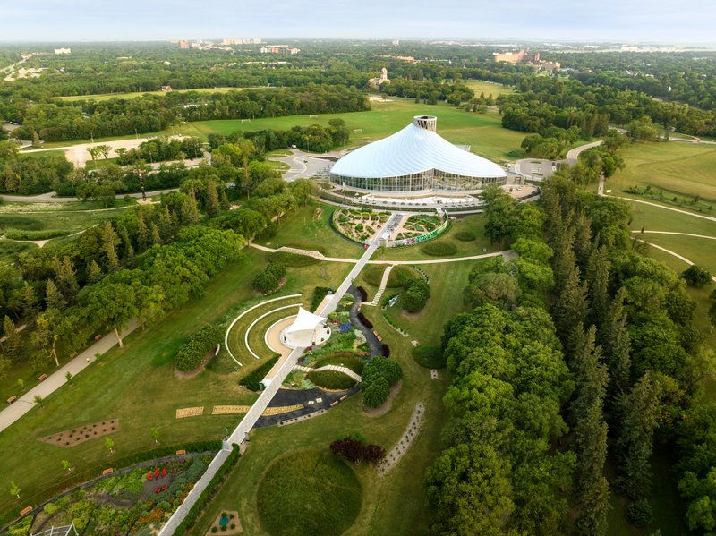 Aerial view of the conical glass conservatory within curved garden paths surrounded by parkland and forest