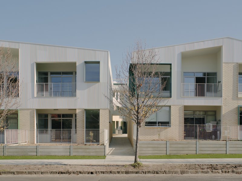 Frontal view showing the central passageway flanked by units with brick base and ribbed upper cladding