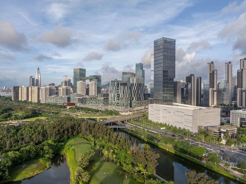 Aerial view of tower cluster beside elevated highway threading through park and waterway