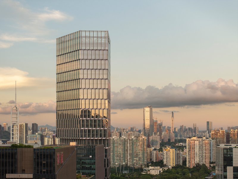Twisted glass tower rising above the urban skyline at dusk with clouds gathering