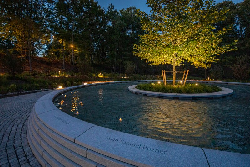 Evening view of the illuminated fountain pools with inscribed coping and lit perimeter planting