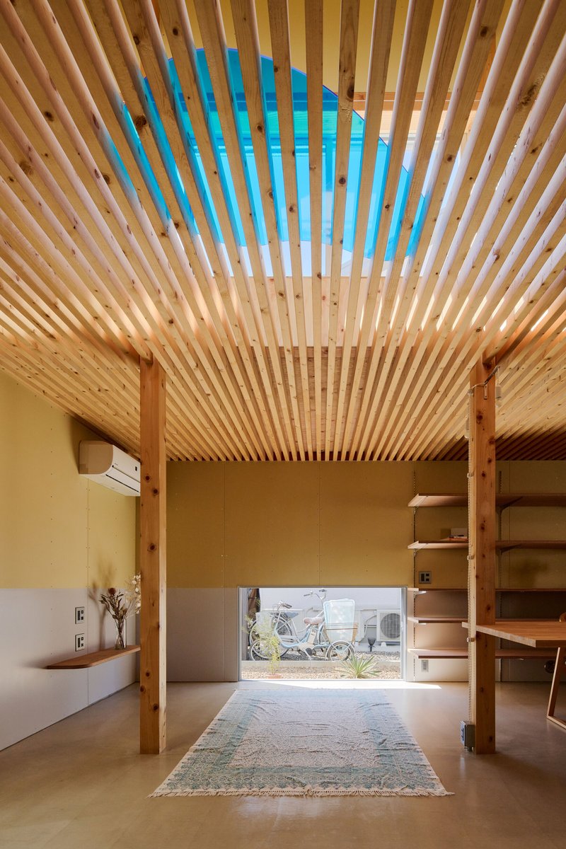 Timber slat ceiling with blue painted section above an open room with view to bicycle outside