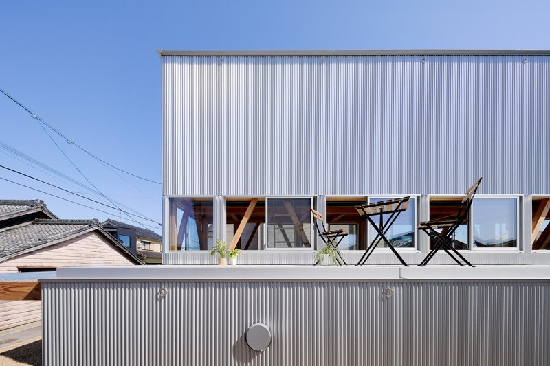 Rooftop terrace with corrugated metal cladding and a pair of folding chairs under clear blue sky