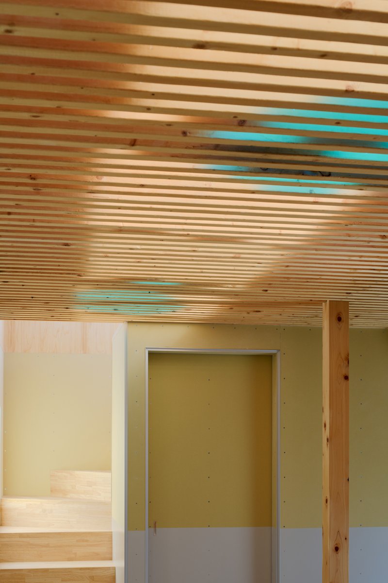 Timber slatted ceiling with turquoise accents above a yellow-walled doorway and pale flooring