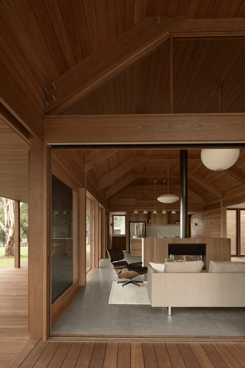 Open-plan living area with exposed timber beams and glazed doors connecting to the exterior deck