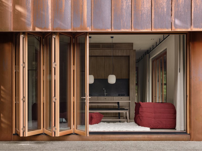 Open folding door threshold revealing interior with dark backsplash and red upholstered seating