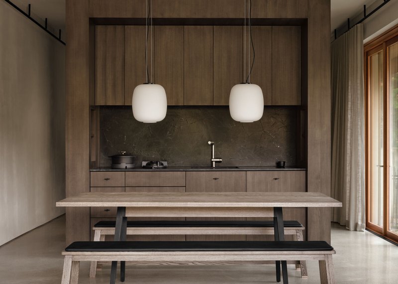 Timber kitchenette wall with stone counter and twin pendant lights above bench seating