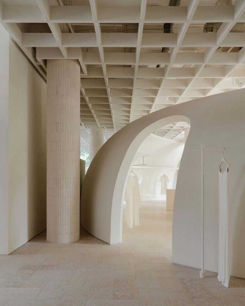 Curved archway framing fluted column and recessed display niches with hanging garments in daylight