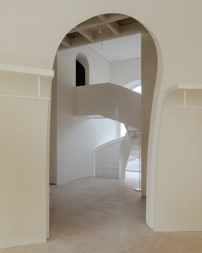 View through rounded arch to the curved staircase ascending to upper levels