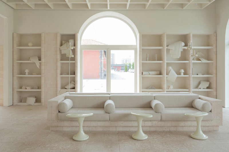 Built-in seating bench beneath arched window with shelving displaying ceramics and models