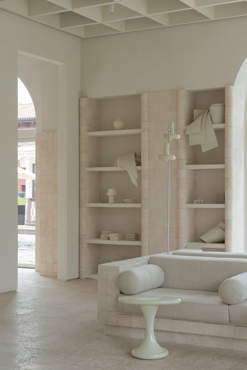 Living area with built-in timber shelving and white floor lamp beneath a coffered ceiling