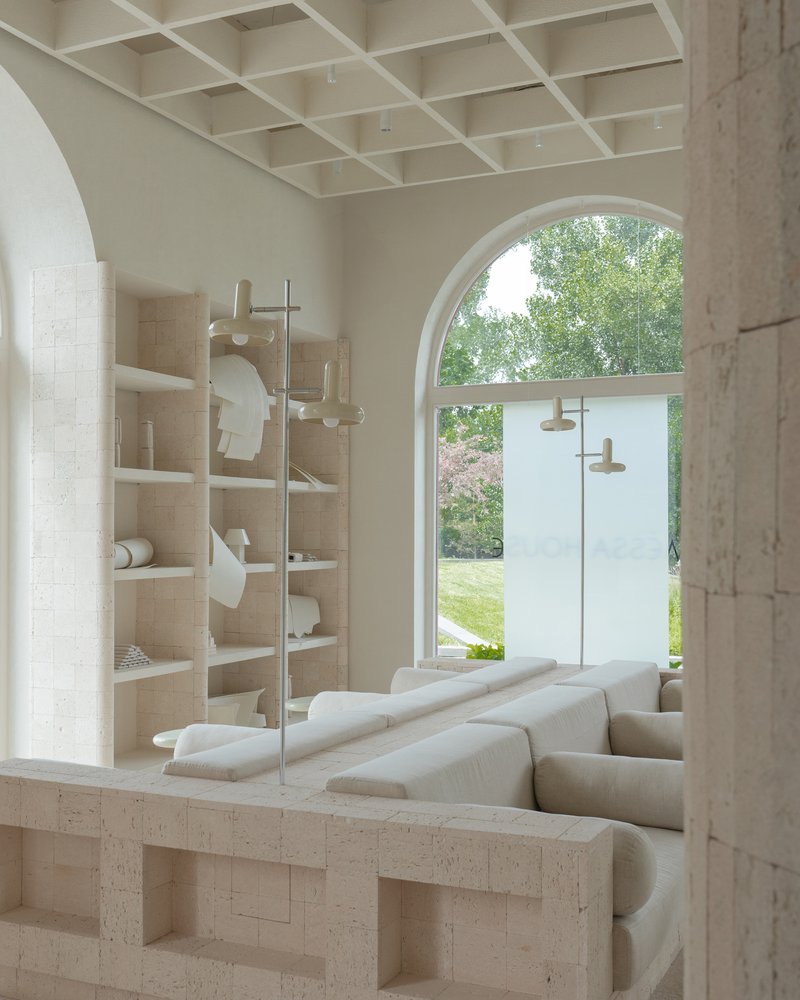 Built-in travertine shelving beside a cushioned seating niche framing an arched window overlooking green lawn