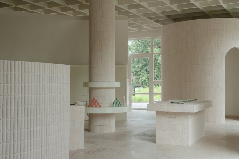 Interior with pale brick columns and coffered ceiling framing a view to the garden beyond