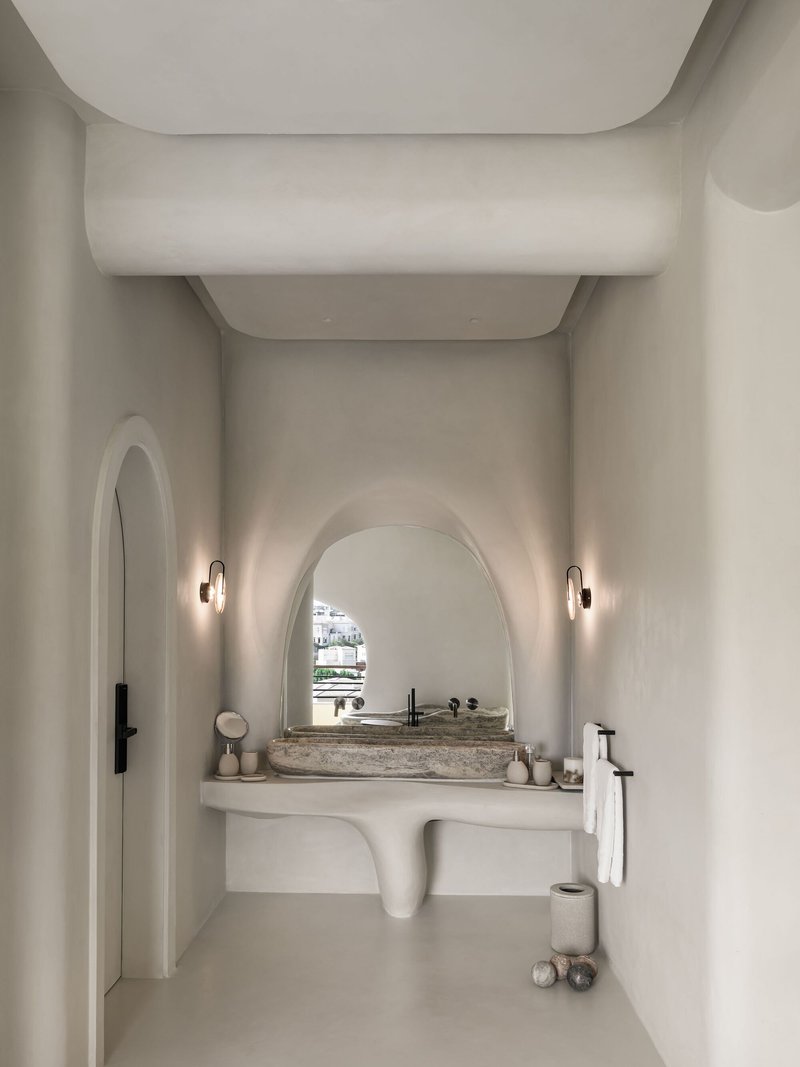 Powder room with arched vanity niche, stone basin and layered curved ceiling volumes