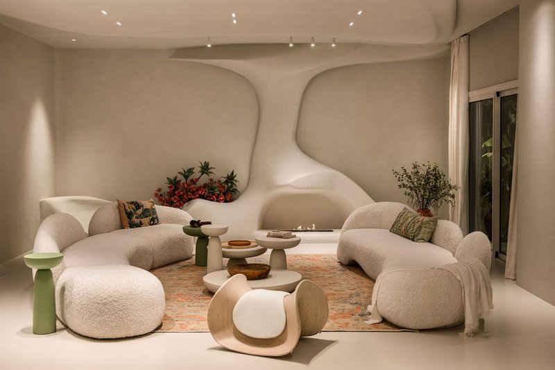 Living room with sculptural ceiling waves and curved seating around low tables under track lighting