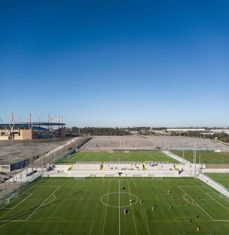 Elevated view of multiple football pitches with players training under a clear blue sky
