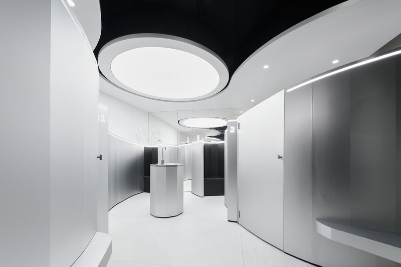 Interior view of white curved walls with circular ceiling light insets and a central cylindrical reception desk