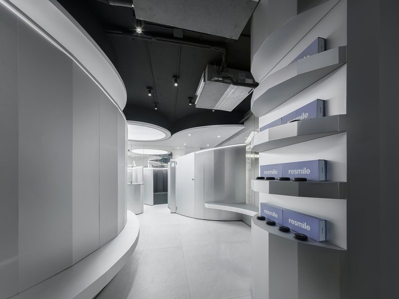 Product display shelves with branded boxes mounted on a grey wall beside curved white partitions