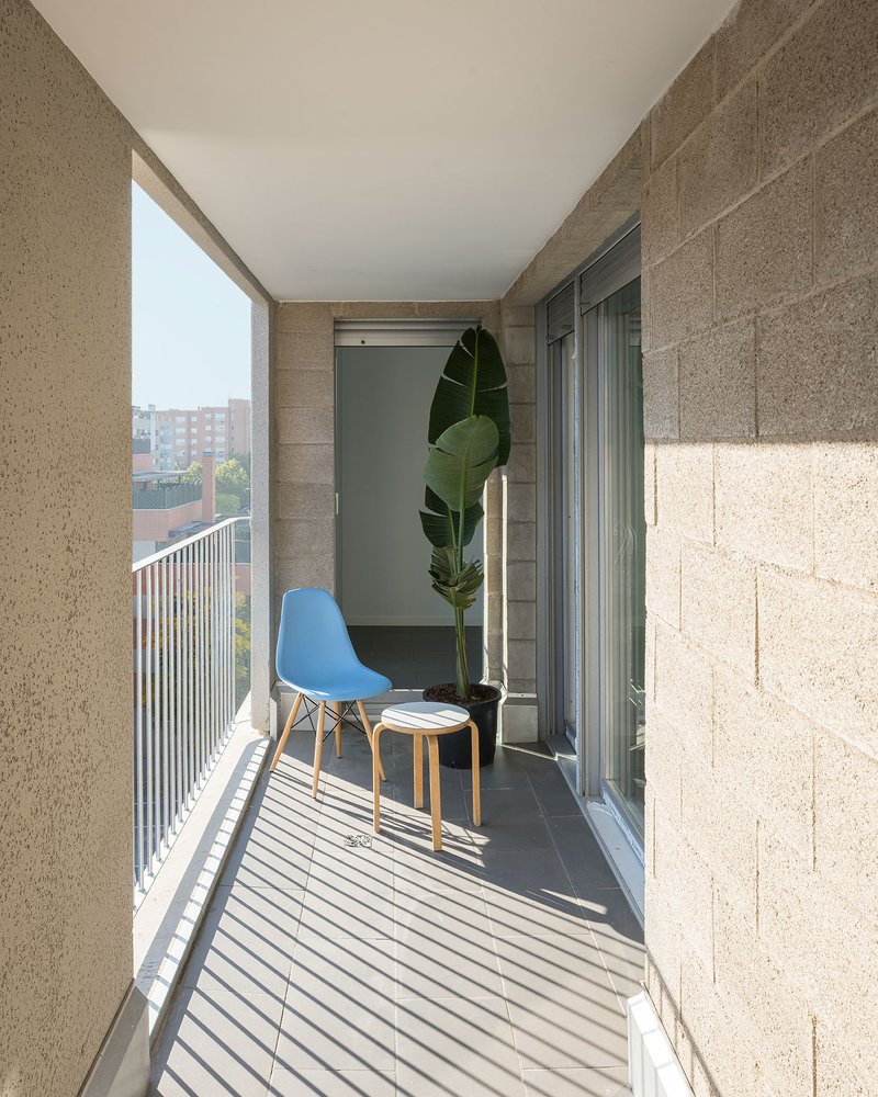 Narrow balcony with hempcrete block walls and vertical metal railings casting striped shadows