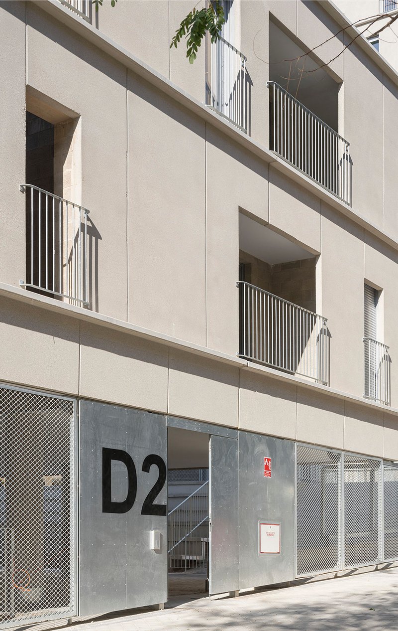 Ground-floor entrance with perforated metal screens and a metal door marked with building signage