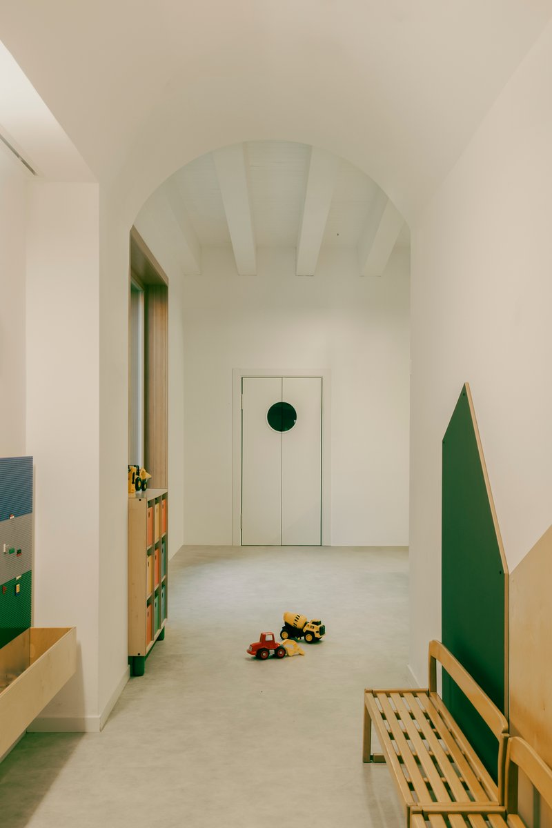 Arched corridor with exposed ceiling beams leading to a door with circular green detail