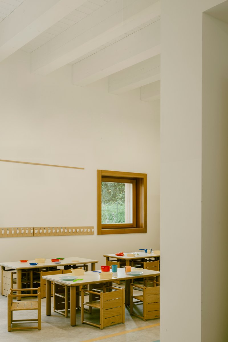 Classroom interior with timber furniture and exposed beam ceiling framed through a doorway