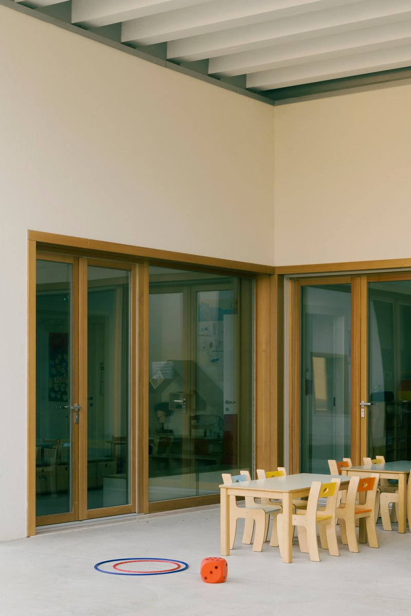 Corner terrace with timber framed glazing and exposed beam ceiling overlooking children's furniture and toys