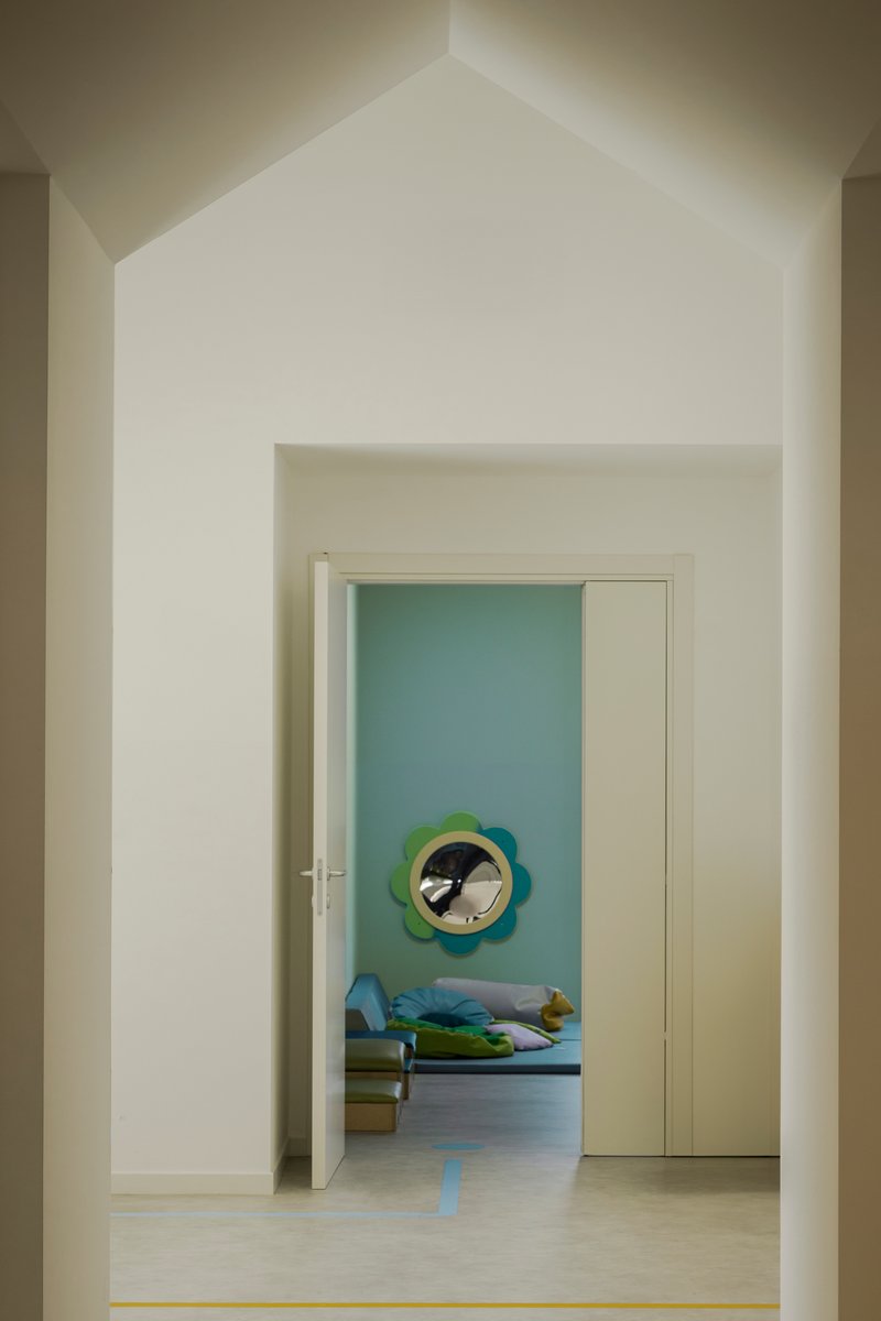 View through a doorway with gabled ceiling into a sleeping room with a circular wall mirror