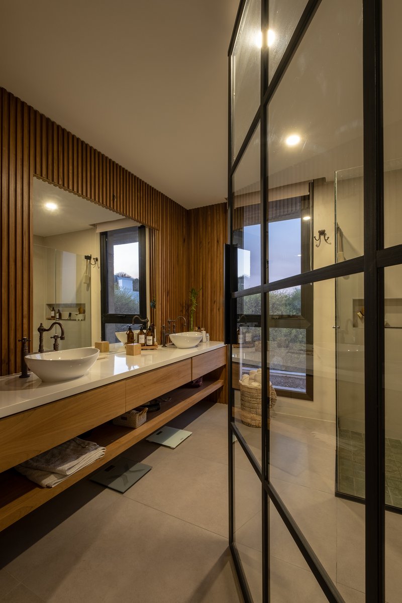 Bathroom with timber slat wall, floating vanity, and steel-framed glass shower enclosure at dusk