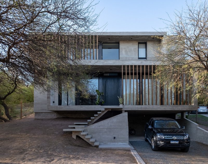 Two-story concrete residence with vertical timber screen and cantilevered entrance stair above a semi-basement garage